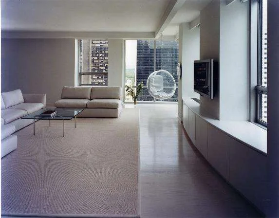 Minimal high-rise living room with pale sofas, a glass coffee table and a hanging bubble chair before city windows