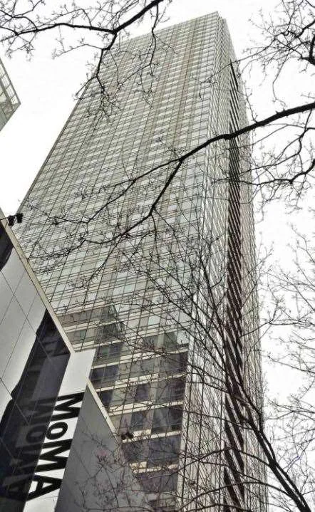 Museum Tower, a glass residential tower, rising above the Museum of Modern Art behind bare winter branches